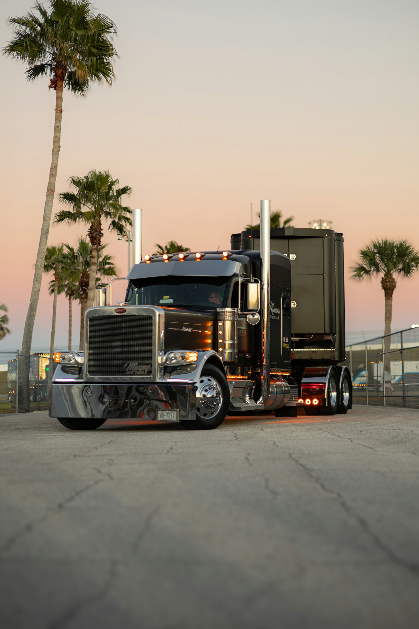 Black semi truck parked beside palm trees in Daytona Beach, Florida